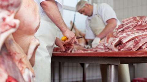 Zwei Metzger zerlegen Fleisch in einer Metzgerei.